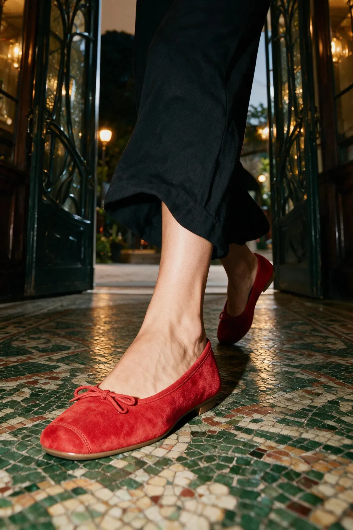 Red suede ballet flats walking across the mosaic floor of a Paris arcade.